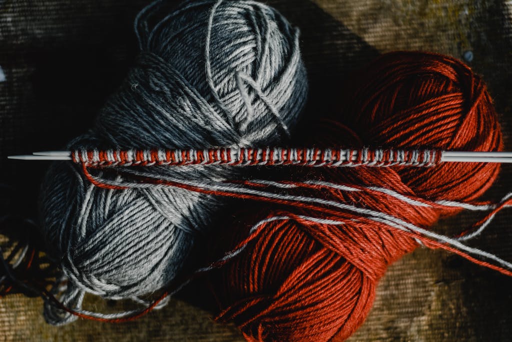 Close-Up Shot of Knitting Needles and Yarn Rolls
