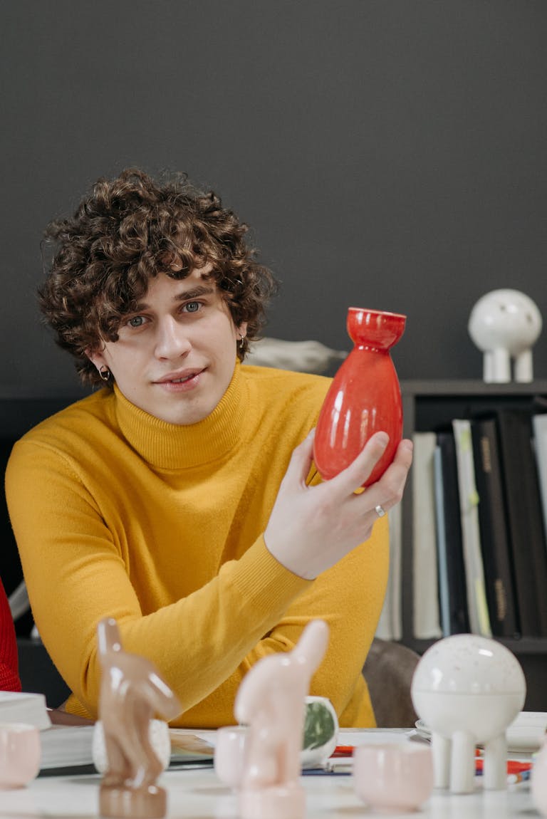 Man in Yellow Sweater Holding a Vase