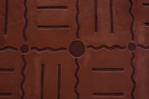 Abstract design with geometric patterns on a textured brown wall surface.