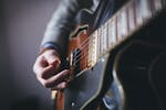 A detailed shot of a musician's hand strumming an electric guitar.