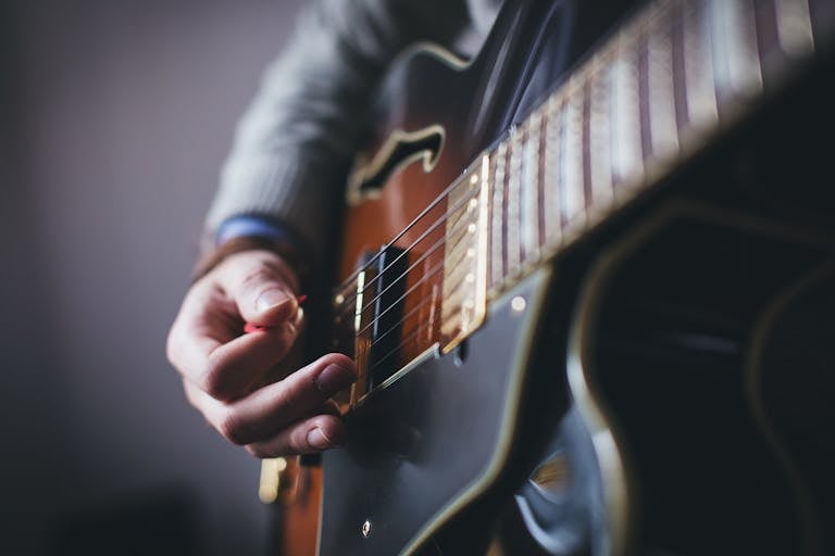 A detailed shot of a musician's hand strumming an electric guitar.