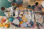 Colorful art supplies including acrylic tubes and brushes on a creative workspace.