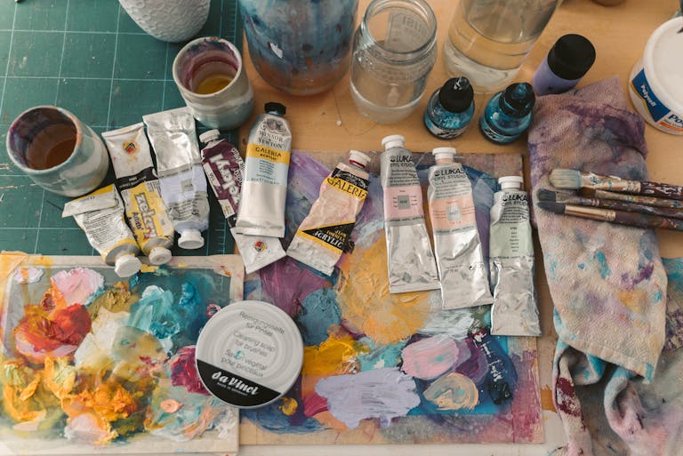 Colorful art supplies including acrylic tubes and brushes on a creative workspace.