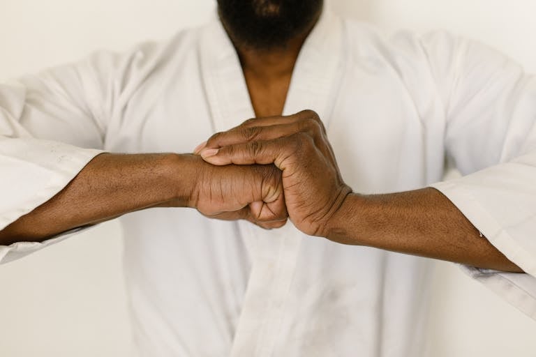 Close-up of a martial artist's hands clasped in a traditional martial arts gesture.