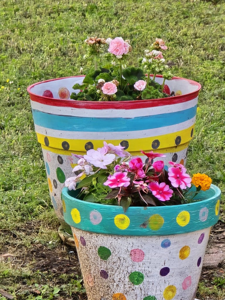 Vibrant flower pots with polka dots brighten a lush garden area.