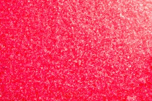 Close-up of vibrant pink crystals forming a textured background.