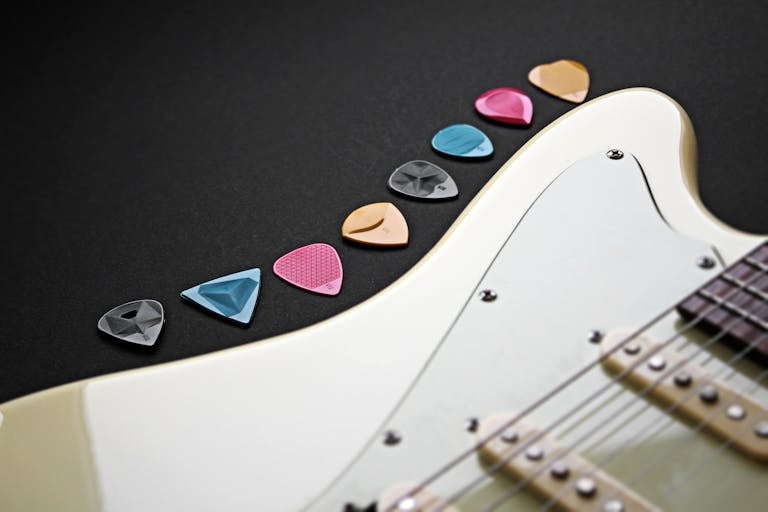 Close-up of colorful guitar picks on an electric guitar.