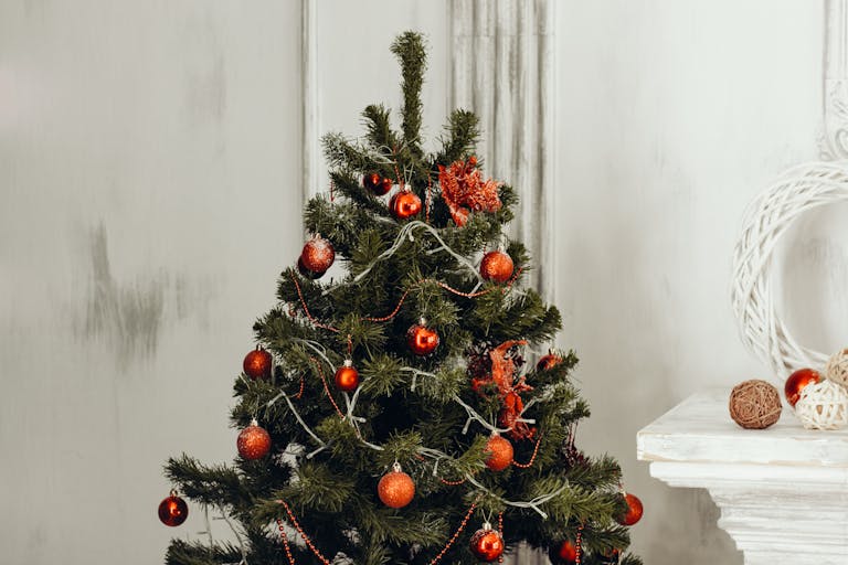 Decorated Christmas tree with red ornaments and warm lighting indoors.