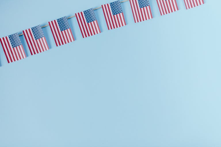 String of American flags on a light blue background.
