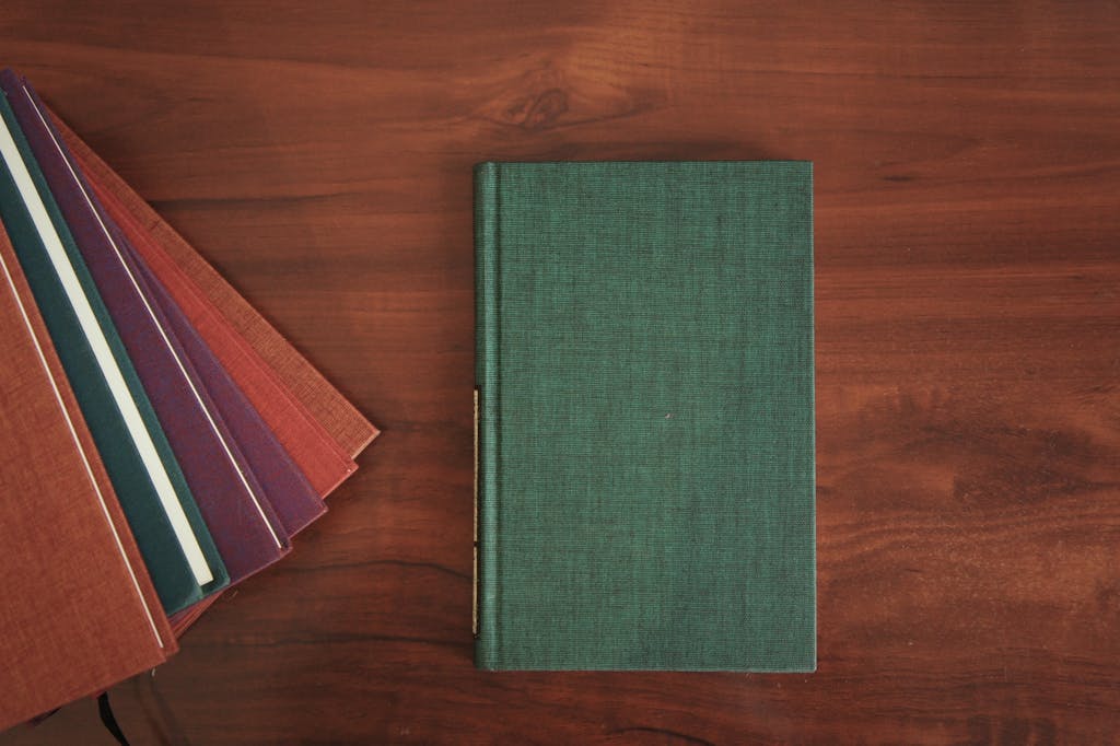A collection of colorful hardcover notebooks arranged on a wooden table.