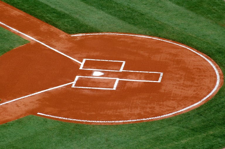 A top-down view of a baseball field's home plate area on a sunny day.