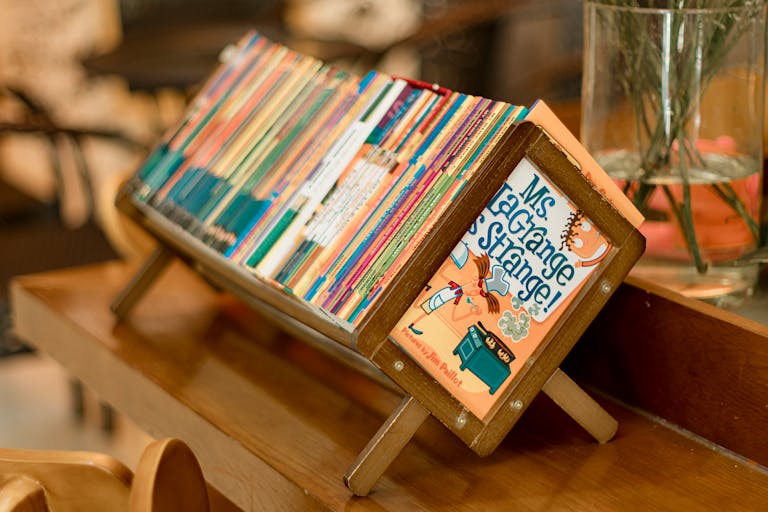 A vibrant collection of children's books on a wooden stand indoors.