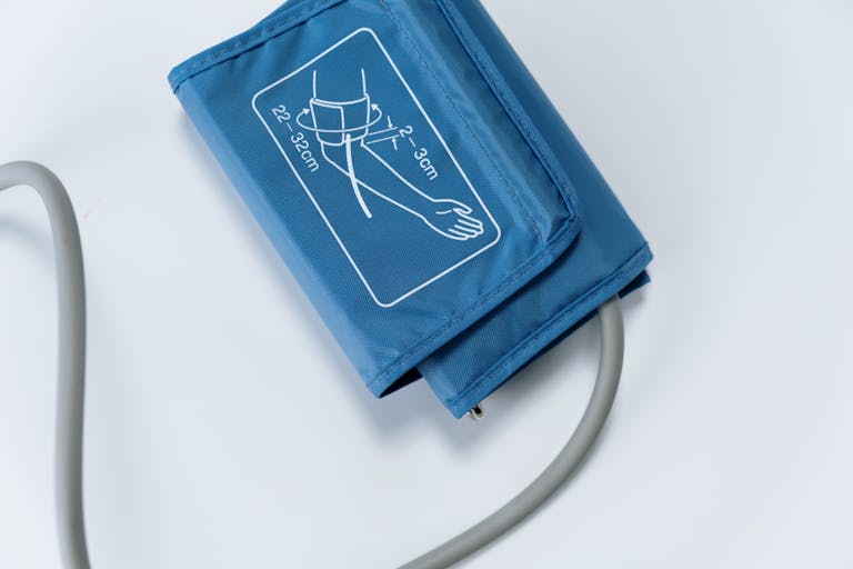 Close-up of a blue blood pressure cuff on a white surface, medical equipment for health monitoring.