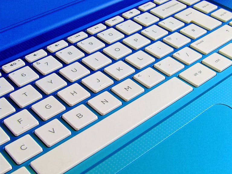 Detailed close-up image of a white computer keyboard on a blue laptop.