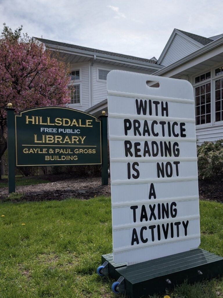 Hillsdale Free Public Library Sign outside the library reads "With practice reading is not a taxing activity."
