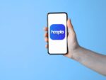 Hand holding mobile phone with Hoopla app icon on phone screen