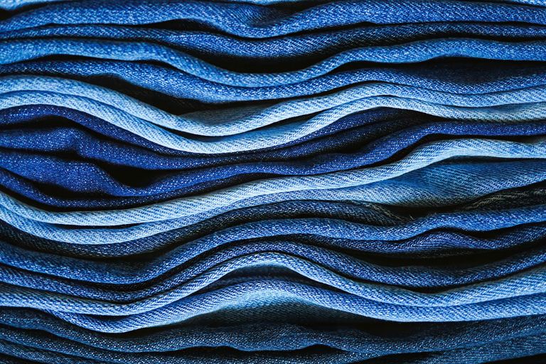 Close-up view of layered blue denim fabrics creating textured waves in various shades.